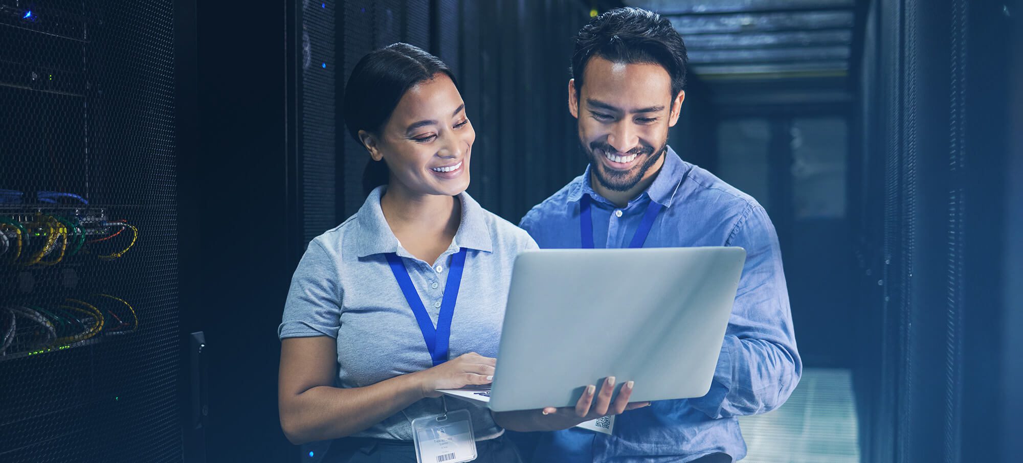 Network administrators working together with Cisco Meraki's SD-WAN on a laptop while in a room with network servers.